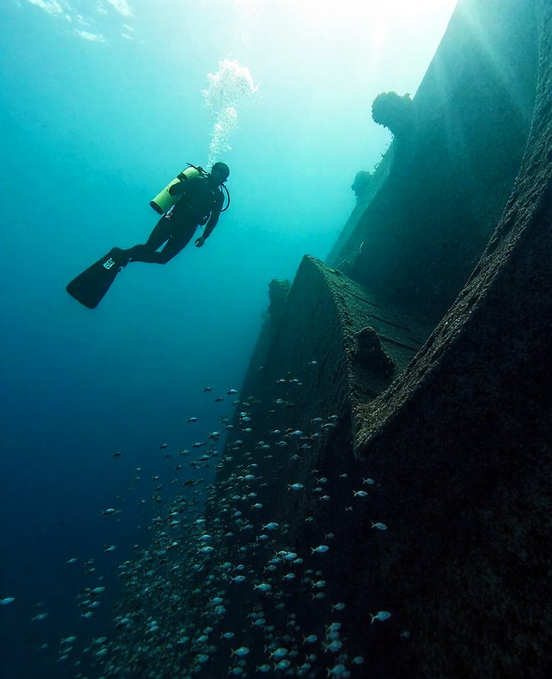 A diver drifting above the broken hull of a wreck off Grande Island